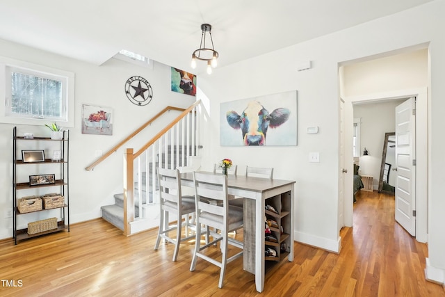 dining area with stairway, baseboards, and wood finished floors