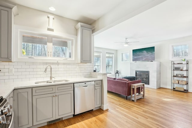 kitchen featuring stove, dishwasher, gray cabinetry, and a sink