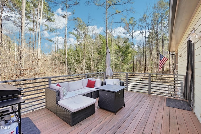 wooden deck with an outdoor living space, a forest view, and a grill