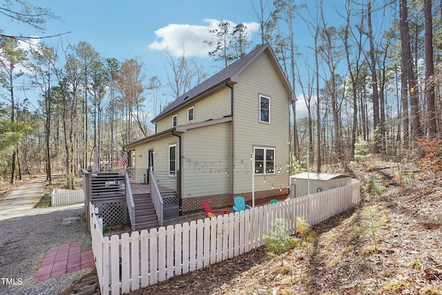 exterior space featuring a wooden deck, stairs, and fence