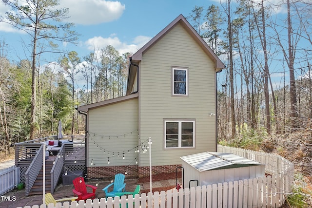 back of house featuring stairway, a deck, and fence