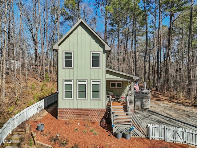 view of outbuilding with stairway, a porch, a fenced backyard, and a wooded view