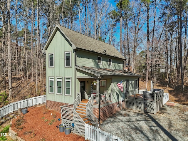 view of front of property featuring a porch, fence, board and batten siding, and a shingled roof