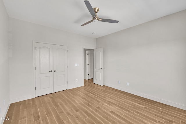 unfurnished bedroom with ceiling fan, a closet, baseboards, and light wood-style flooring