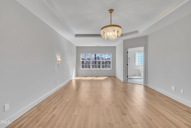 unfurnished room featuring baseboards, light wood-type flooring, a tray ceiling, and ornamental molding