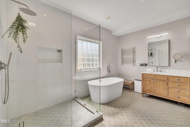 full bathroom with a freestanding bath, vanity, and a tile shower