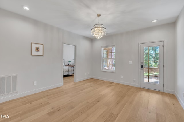 interior space with light wood finished floors, visible vents, a chandelier, and baseboards