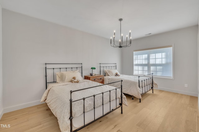 bedroom with visible vents, light wood-style flooring, an inviting chandelier, and baseboards