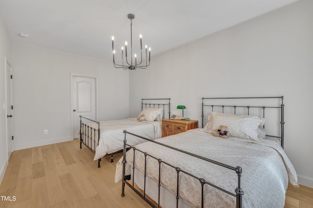 bedroom featuring baseboards, light wood-type flooring, and an inviting chandelier