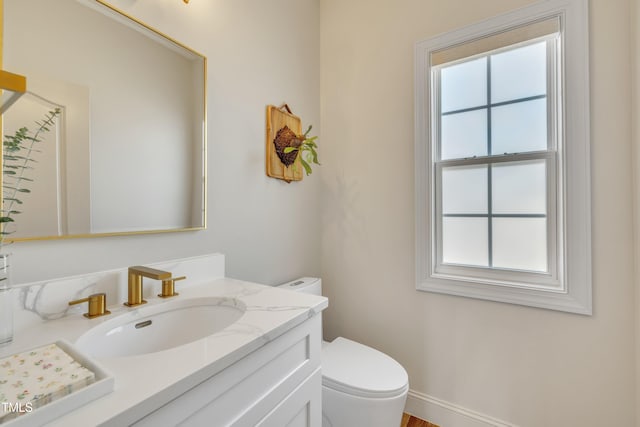 bathroom featuring vanity, toilet, baseboards, and a wealth of natural light