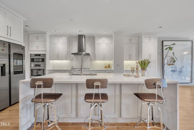 kitchen with appliances with stainless steel finishes, wall chimney exhaust hood, light countertops, and white cabinetry