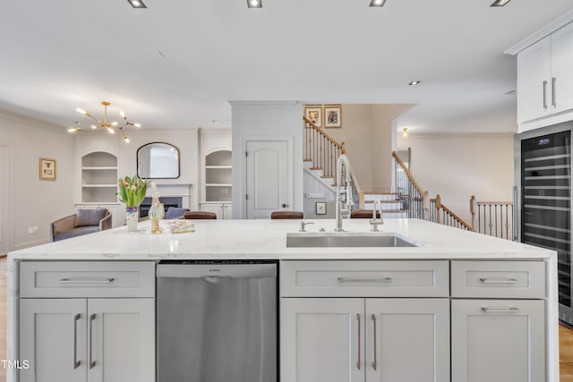 kitchen with built in shelves, crown molding, open floor plan, stainless steel dishwasher, and a sink