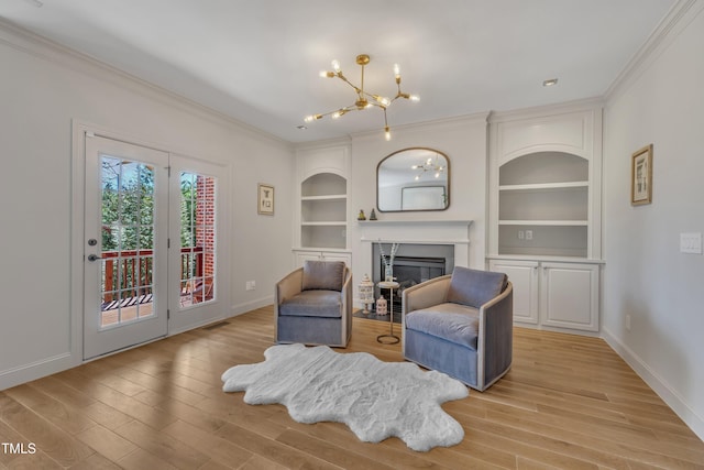 sitting room featuring a glass covered fireplace, built in shelves, light wood-style floors, and ornamental molding