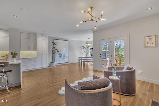 living area with baseboards, light wood-type flooring, an inviting chandelier, and ornamental molding