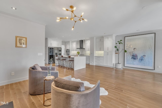 living area with a chandelier, light wood finished floors, baseboards, and ornamental molding