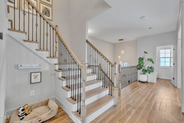 stairs featuring crown molding, baseboards, and wood finished floors