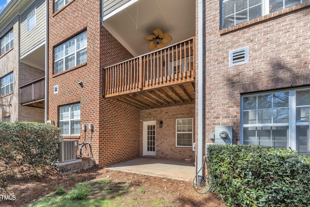 back of property with brick siding, ceiling fan, cooling unit, and a patio