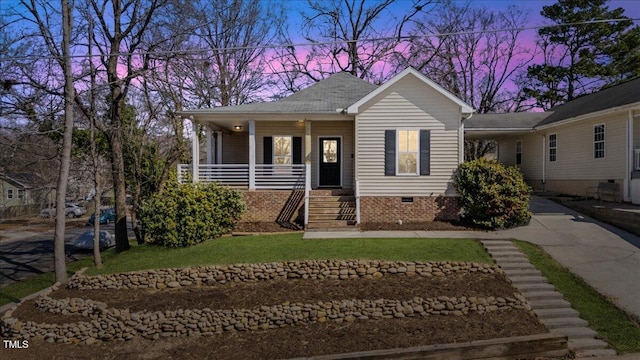 view of front of house featuring a shingled roof, concrete driveway, covered porch, a lawn, and crawl space