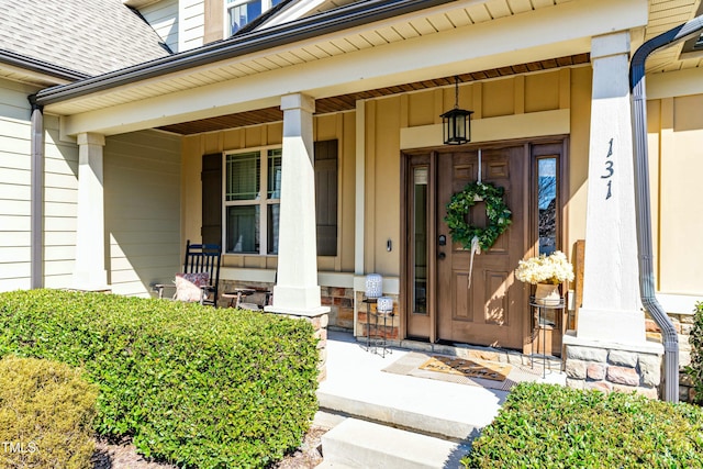 entrance to property featuring covered porch and a shingled roof