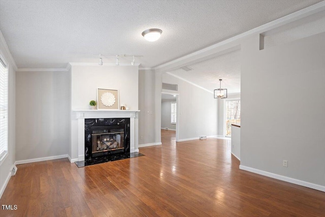 unfurnished living room featuring baseboards, ornamental molding, a premium fireplace, a textured ceiling, and wood-type flooring