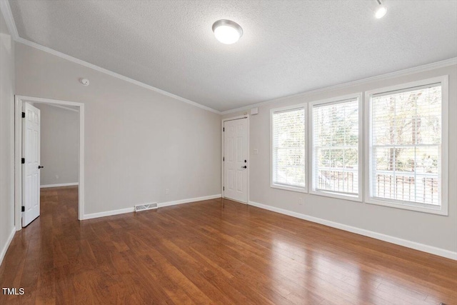 empty room featuring visible vents, a textured ceiling, wood finished floors, and crown molding