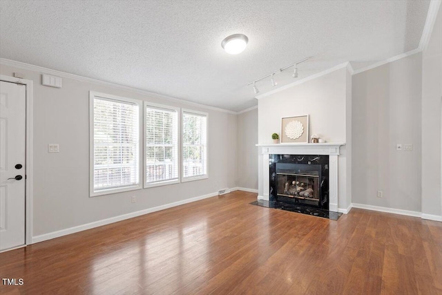 unfurnished living room featuring a premium fireplace, wood finished floors, and crown molding