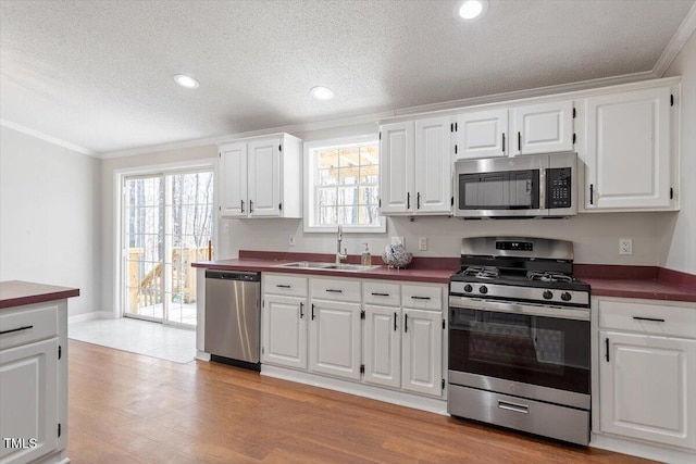 kitchen featuring a sink, dark countertops, plenty of natural light, and stainless steel appliances