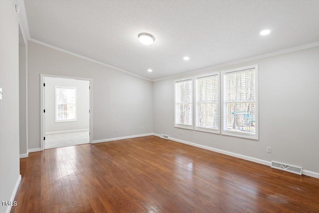 empty room with visible vents, crown molding, and hardwood / wood-style flooring