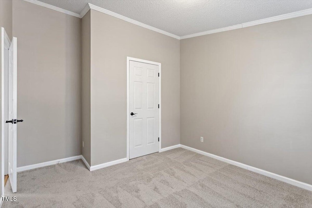 carpeted empty room with a textured ceiling, baseboards, and ornamental molding