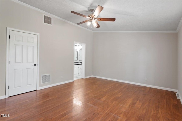 spare room featuring crown molding, wood finished floors, and visible vents