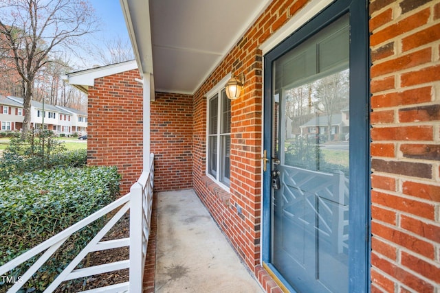 view of exterior entry with brick siding and a residential view