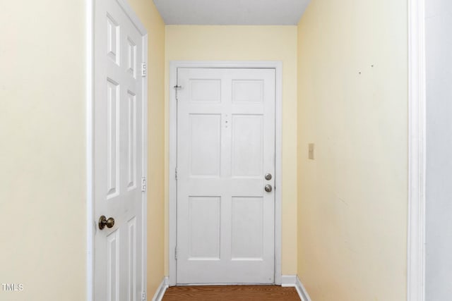 doorway with baseboards and wood finished floors