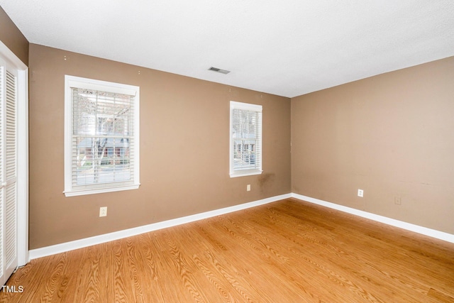 empty room featuring visible vents, baseboards, and light wood-style flooring