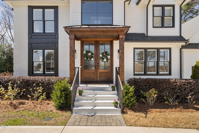 property entrance with french doors, brick siding, and roof with shingles