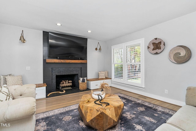 living room with a brick fireplace, recessed lighting, wood finished floors, and baseboards