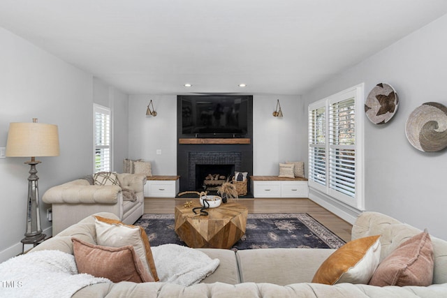 living area featuring recessed lighting, a large fireplace, plenty of natural light, and wood finished floors