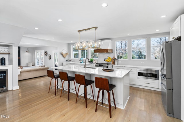 kitchen with a breakfast bar area, a sink, stainless steel appliances, white cabinetry, and light wood-type flooring