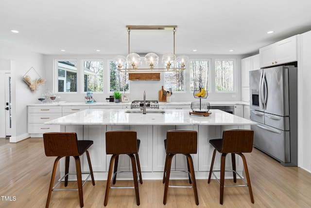 kitchen with a sink, a healthy amount of sunlight, white cabinets, and stainless steel fridge with ice dispenser