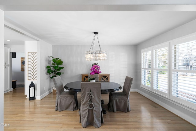 dining space featuring an inviting chandelier, baseboards, and light wood finished floors