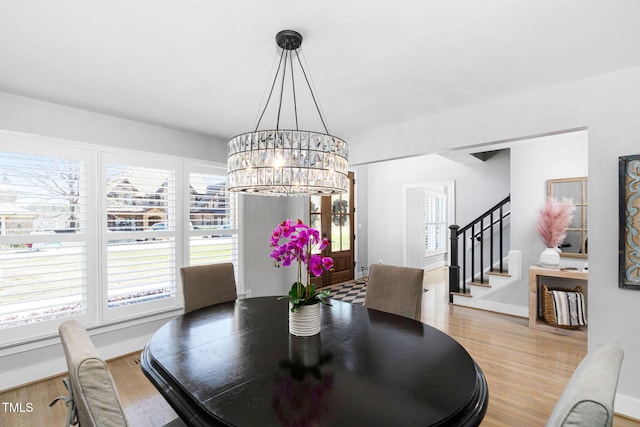 dining area featuring stairway, baseboards, an inviting chandelier, and wood finished floors