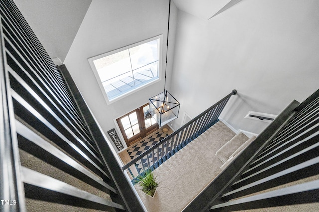 stairs featuring carpet flooring, a high ceiling, and a notable chandelier