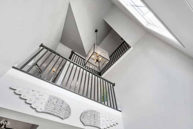 staircase with a chandelier and high vaulted ceiling