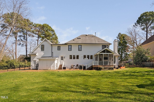 rear view of property featuring a fenced backyard, a chimney, a yard, and a sunroom