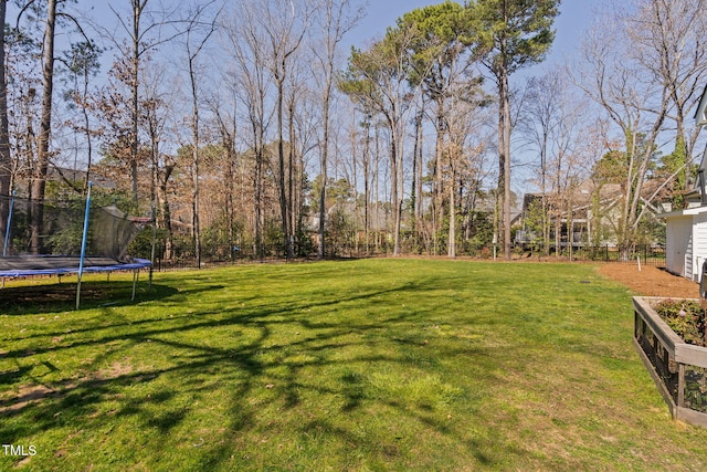 view of yard featuring a trampoline and fence