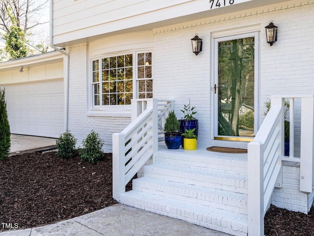 entrance to property with a garage and brick siding