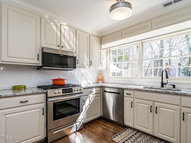 kitchen with visible vents, backsplash, dark wood-style floors, stainless steel appliances, and a sink