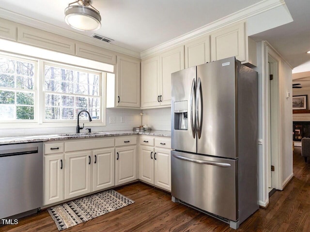 kitchen with visible vents, light stone counters, appliances with stainless steel finishes, dark wood-style floors, and a sink