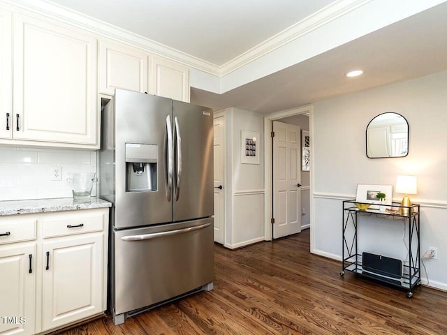 kitchen with dark wood-style floors, ornamental molding, stainless steel fridge, white cabinets, and tasteful backsplash