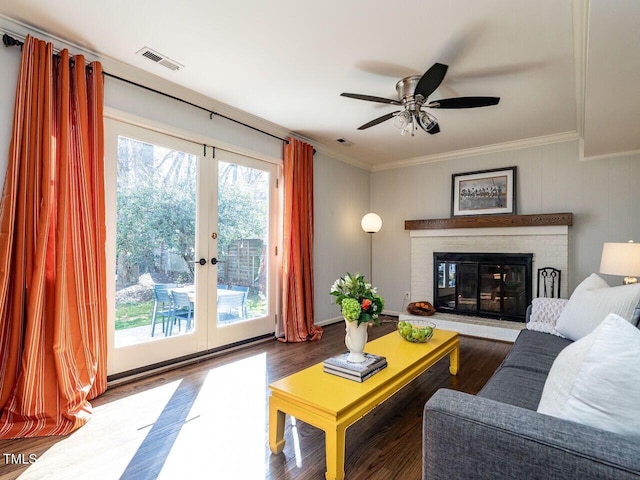 living area with visible vents, ornamental molding, wood finished floors, french doors, and a fireplace