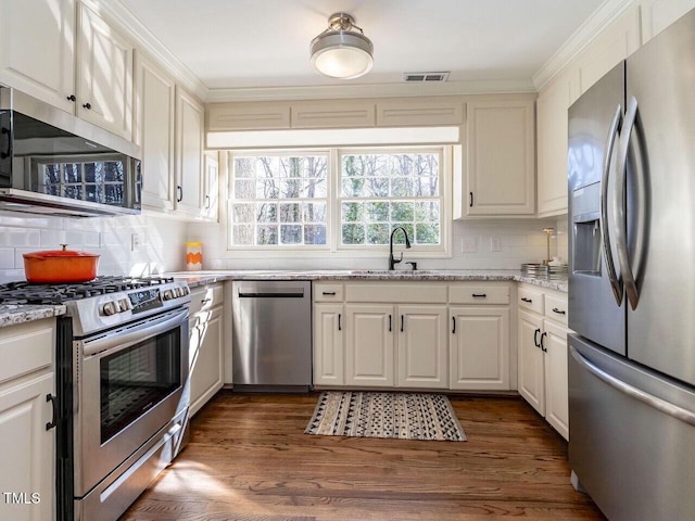 kitchen featuring visible vents, backsplash, white cabinets, stainless steel appliances, and a sink